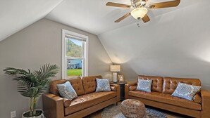 A room with two brown leather sofas, a ceiling fan, a large window, a potted plant, and a round rug. - Delightful Appalachian Trail 2-bedroom lodge with AC in Central Damascus (Damascus)