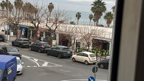 Vista de la calle con una glorieta, coches aparcados, una camioneta azul y una noria al fondo.