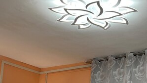 Un baño con inodoro, televisor montado en la pared y lámpara en el techo.