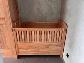 A wooden bench with a slatted design, positioned against a wall with a textured surface.