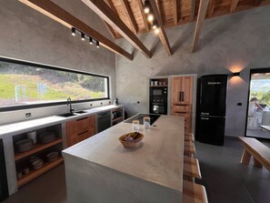 A modern kitchen with a large island, wooden cabinets, and a view of the outdoors.