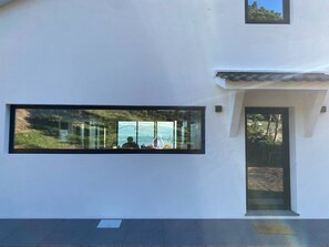 A modern building with large windows, a door, and a small balcony. - Casa     do   Atalho (SÃO ROQUE DO PICO)