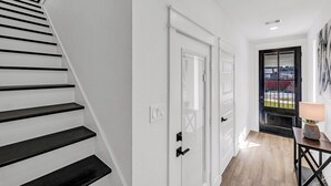 Una escalera con escalones negros que lleva a una puerta blanca.