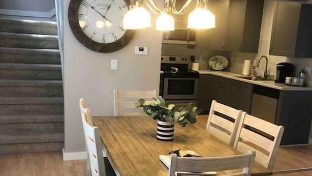 Ein Essbereich mit einem Holztisch, vier Stühlen, einer Uhr und einem Kronleuchter.
