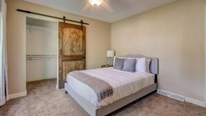 Une chambre à coucher avec un lit, un ventilateur de plafond, une table de chevet et une porte en bois.