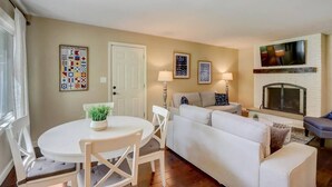 Un salon avec un canapé blanc, une table à manger avec des chaises et une cheminée.