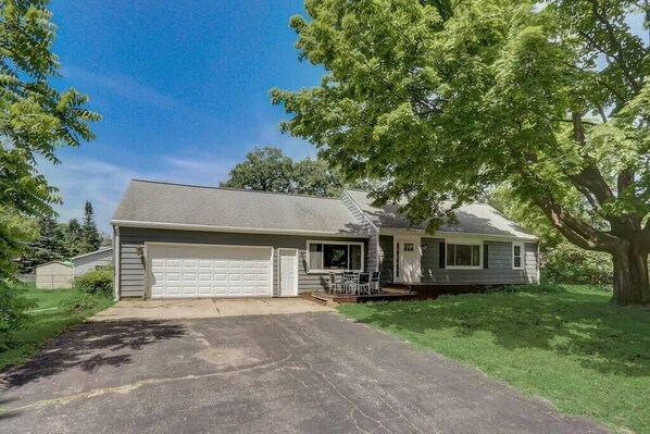 A single-story house with a garage, a covered patio, and a large tree in the front yard. - Charming Muskego House, Walk to Lake & Restaurants (Muskego)