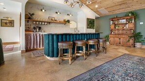 Een keuken met een bar, houten krukken en een decor kast.
