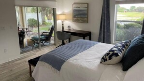 Een slaapkamer met een bed, bureau, stoel en uitzicht op de omgeving.