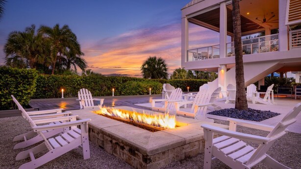 Un espace aménagé au bord de la piscine, avec des chaises longues blanches et un foyer.