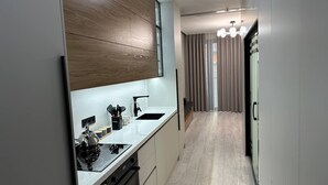 Une cuisine moderne dotée d’un évier à deux bacs, de meubles en bois et d’une hotte en acier inoxydable.