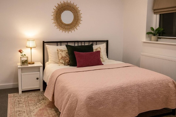 Unwind in the bedroom with layered bedding, cushions, and soft bedside lighting