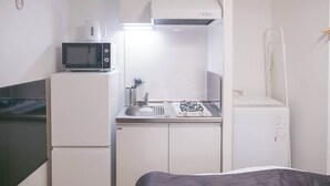 A compact kitchenette with a microwave, stove, and sink. - Triphome Shinokubo WUJI New Open (Shinjuku City)