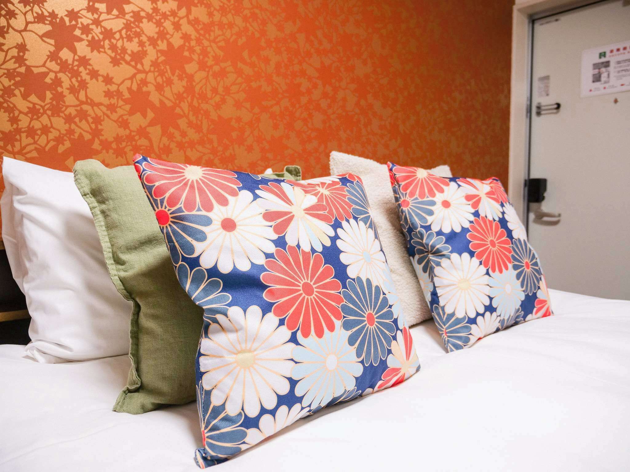 A bed with three pillows in a hotel room.