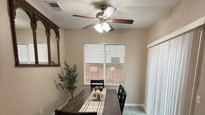 A dining area with a wooden table, chairs, a ceiling fan, and a large mirror on the wall. - Spacious 5 bedroom House-Perfect for Families & Groups (Turlock)