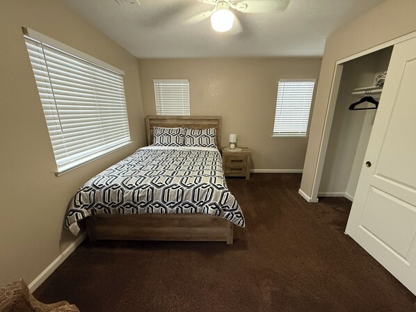 A bedroom with a bed, two bedside tables, a nightstand, and a closet. - Spacious 5 bedroom House-Perfect for Families & Groups (Turlock)