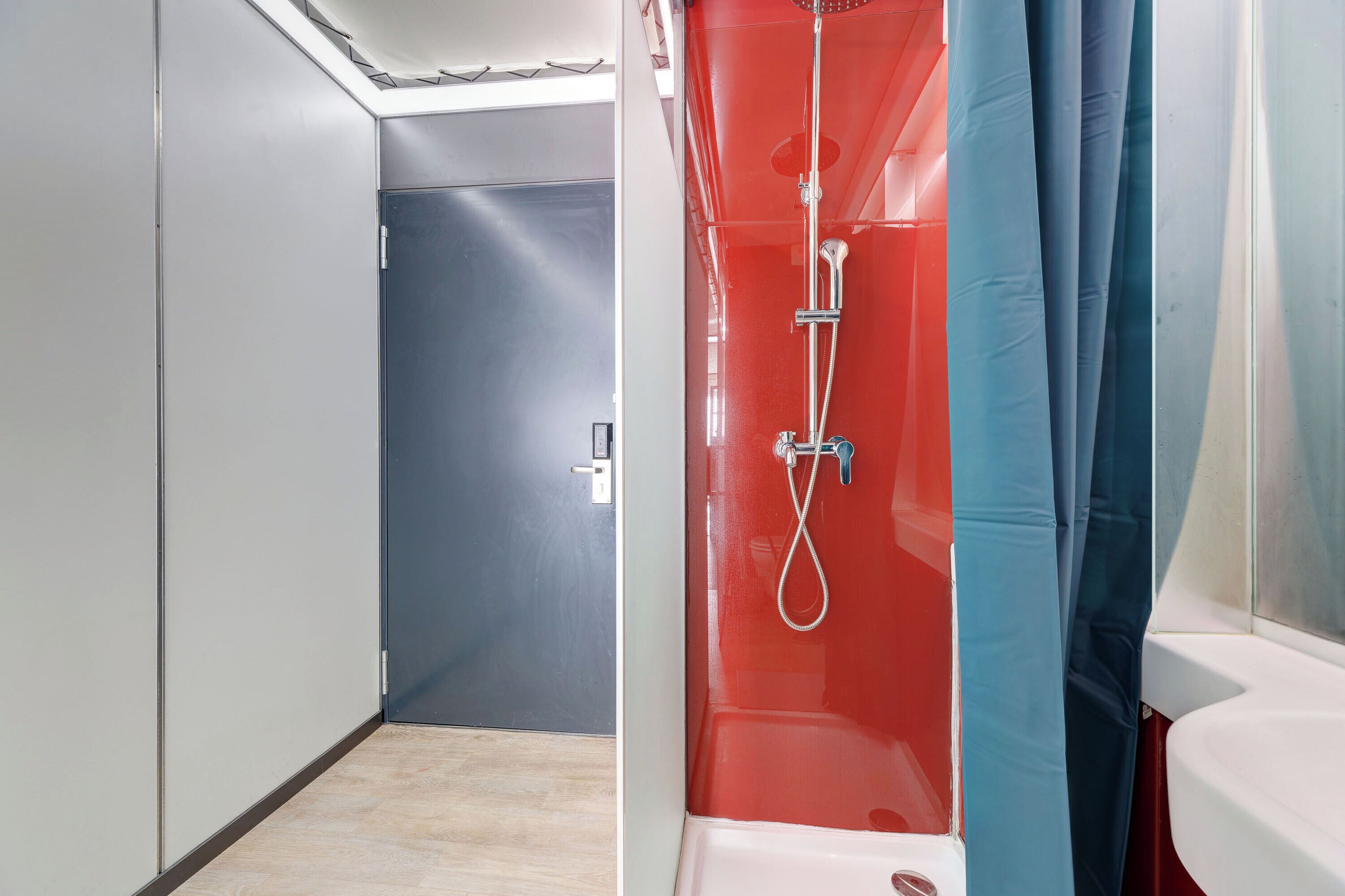 Un bagno moderno con cabina doccia, WC e una porta che conduce in un'altra stanza.