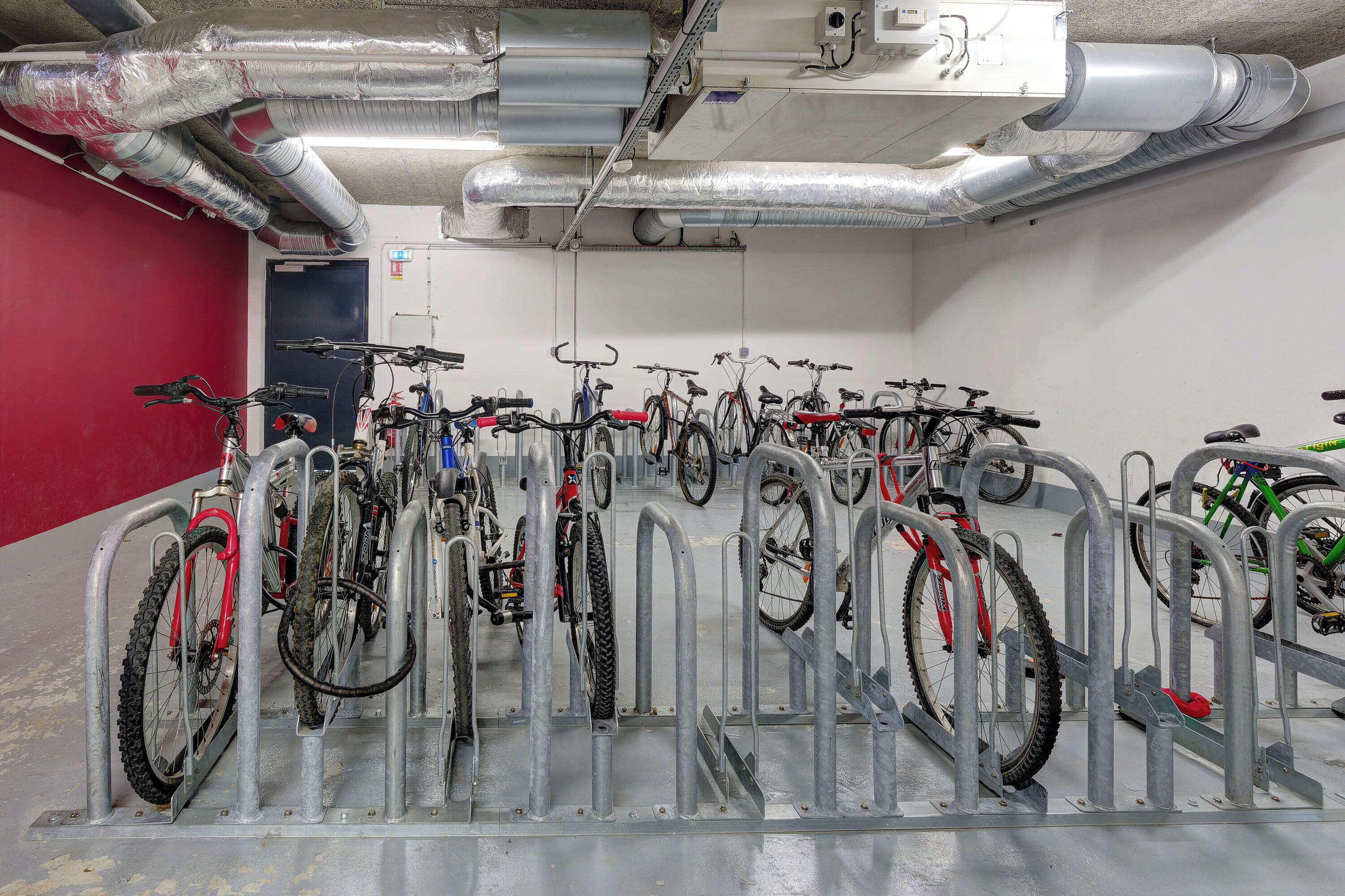 Un área de aparcamiento para bicicletas con varias bicicletas aseguradas a soportes metálicos.