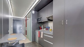 Une cuisine de taille réduite avec des meubles gris, un four à micro-ondes et un petit plan de travail.