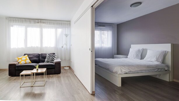 Un dormitorio moderno con cama, sofá y una mesita.
