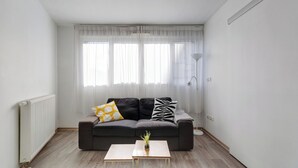 Una sala de estar moderna con un sofá de color gris oscuro, una mesita de madera y una planta en maceta.