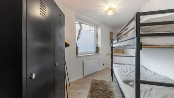 A bunk bed room with a wardrobe, a window, and a radiator.