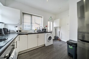 Una cocina moderna con lavadora, refrigerador y cafetera.