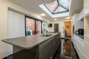 A modern kitchen with a skylight, a built-in island, and a view of the outside.