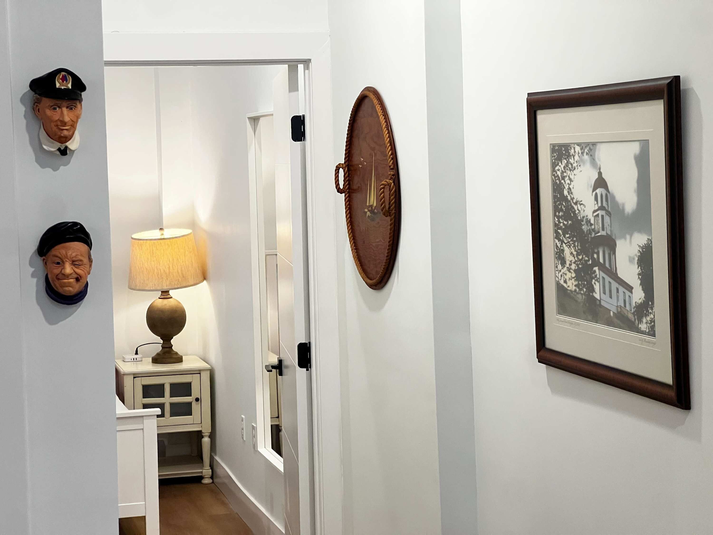 Un couloir avec une lampe, une photographie encadrée et deux éléments décoratifs fixés au mur.