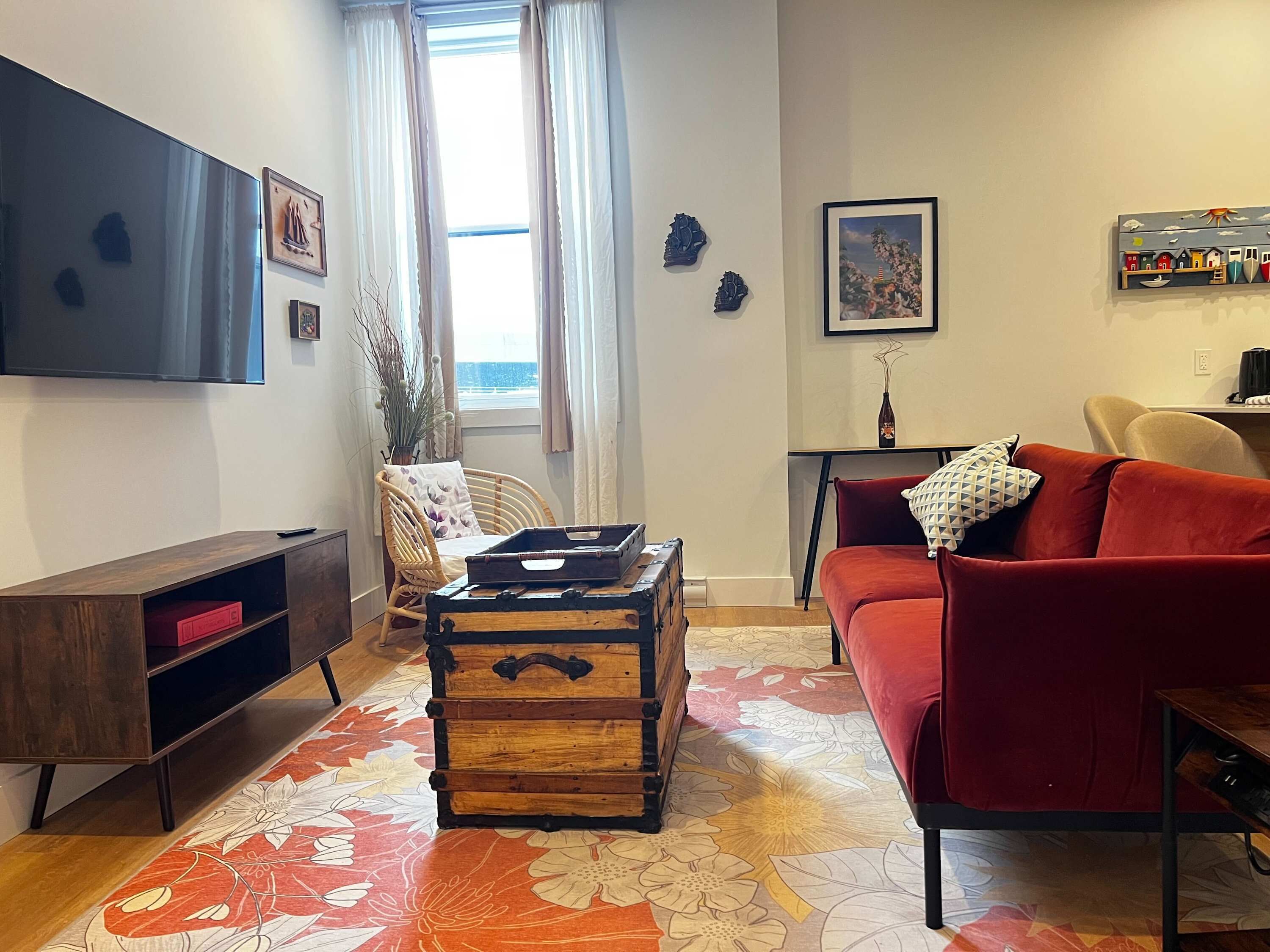 Ein Wohnzimmer mit rotem Sofa, Couchtisch aus Holz und einem an der Wand befestigten Flachbildfernseher.