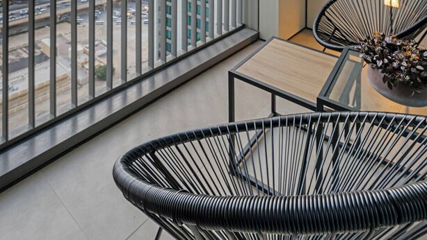 Ein moderner Balkon mit Blick auf die Stadt, ausgestattet mit einem Tisch und zwei Stühlen.