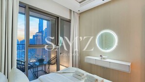 Ein Hotelzimmer mit einem großen Bett, einem Schminktisch mit Spiegel und einem Balkon mit Blick auf die Stadt.
