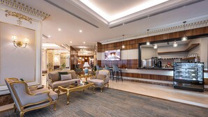 A hotel lobby with a seating area, a bar, and a television screen. - Braiden Hotel (Al Jubail)