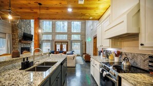 Une cuisine moderne dotée de plans de travail en granit, d’un four encastré et d’une cheminée en pierre.