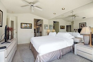 A hotel room with a bed, bedside lamps, a ceiling fan, a TV, and a dresser. - Exclusive 2BR, Golf Views & Private BBQ (Palm Desert)