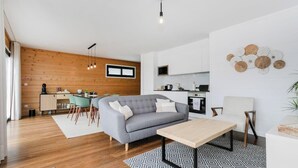 A modern living room with a grey sofa, a wooden coffee table, and a patterned rug. - GuestReady - Good Vibes | Sea Views, Terrace & BBQ (Ponta Delgada)