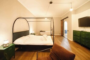 A bedroom with a four-poster bed, a green nightstand, a brown chair, a TV, and a green dresser. - BuddyRent - Vasca - Prati - 4 (Roma)