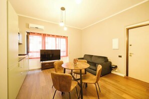 A compact living space with a dining area, a sofa, a television, and a kitchenette. - BuddyRent - Vasca - Prati - 4 (Roma)