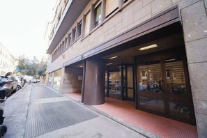 Ein Gebäude mit großem Eingangsbereich, überdachtem Außenbereich und Parkplatz.