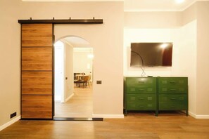 Ein Flur mit einer Schiebetür, einem grünen Aktenschrank und einem Wand-Fernseher.