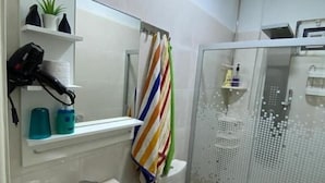A bathroom with a sink, toilet, and shower. There are shelves with toiletries and a mirror above the sink. - Jordan Guest House (Wadi Musa)
