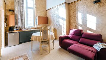 A compact living space with a dining area, a sofa, and a kitchen.