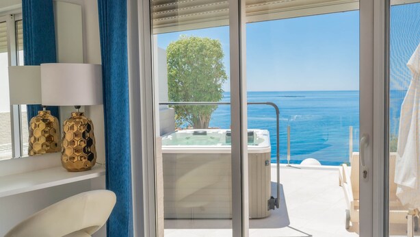 Un balcon avec un jacuzzi, un arbre et une vue sur l’océan.