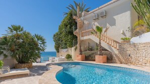 Une piscine à bords incurvés, avec un escalier, et une vue sur la mer.