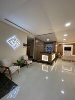 A modern reception area with a reception desk, seating area with chairs, and a large illuminated logo on the wall.