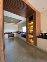 A modern kitchen with wooden accents, built-in shelves, and a sleek countertop.
