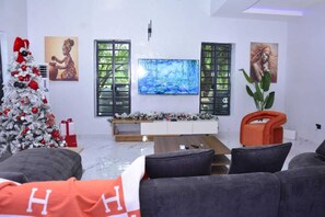A living room with a Christmas tree, a flat-screen TV, and artwork on the walls. - Jazmine's Place. Spacious 5-bedroom building in peaceful  Badore Ajah with AC (Lagos Island)