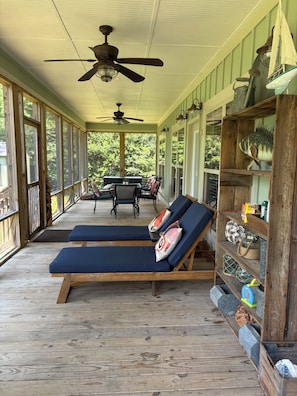 A covered porch with two lounge chairs, a table, chairs, and a ceiling fan. - Lake Therapy Cottage with 3bds/2baths with exceptional Lake Front Views. (Scottsboro)