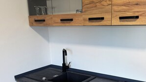 Une cuisine avec des meubles de rangement en bois, un plan de travail noir et un évier.