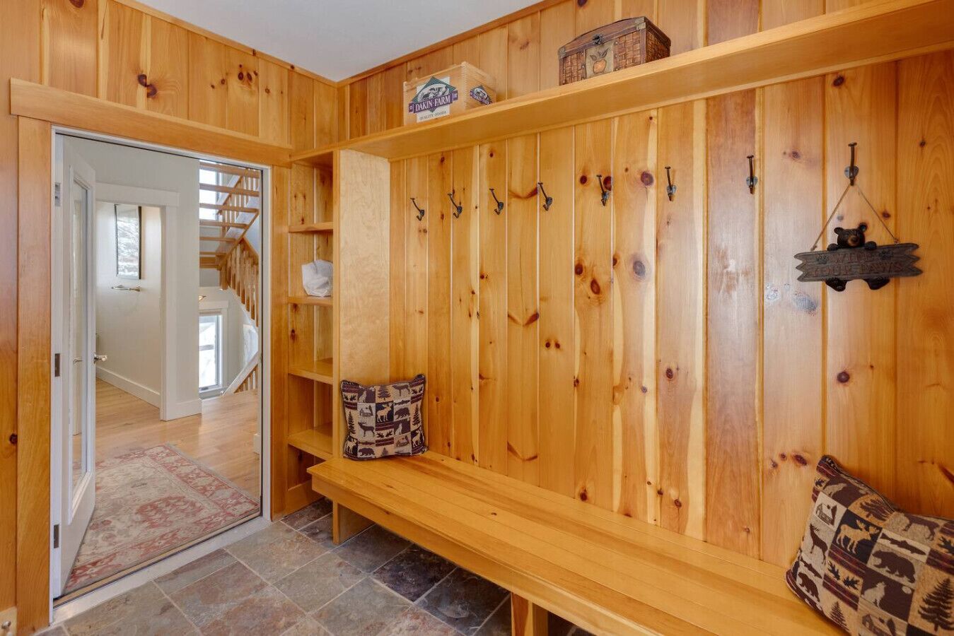 A wooden interior with a bench, shelves, and hooks.